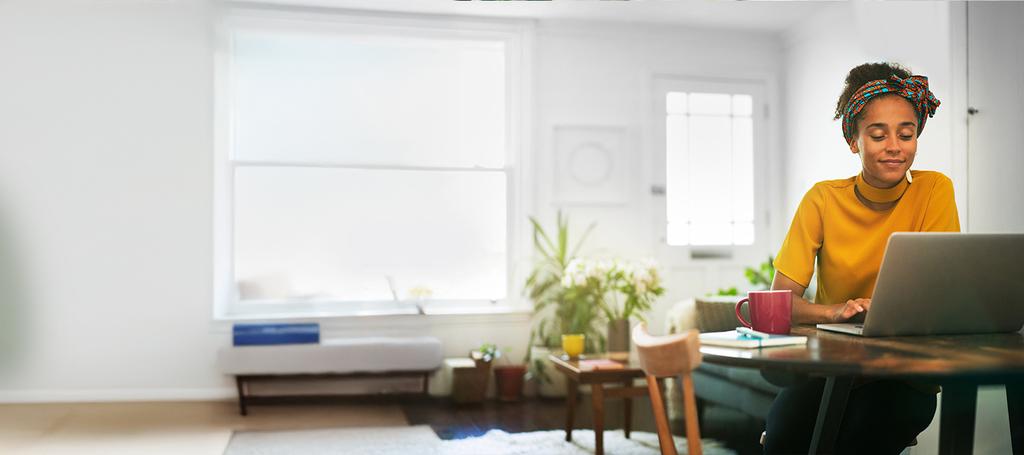 Vrouw zit in woonkamer aan de keukentafel met een laptop