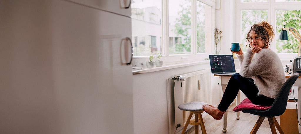 Vrouw op stoel bij radiator met laptop op de achtergrond